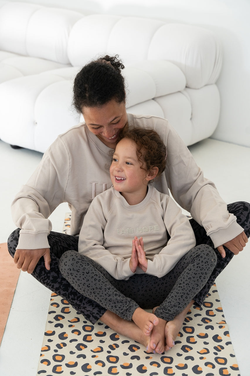Mama und Kind machen die Yoga-Schmetterlingspose gemeinsam